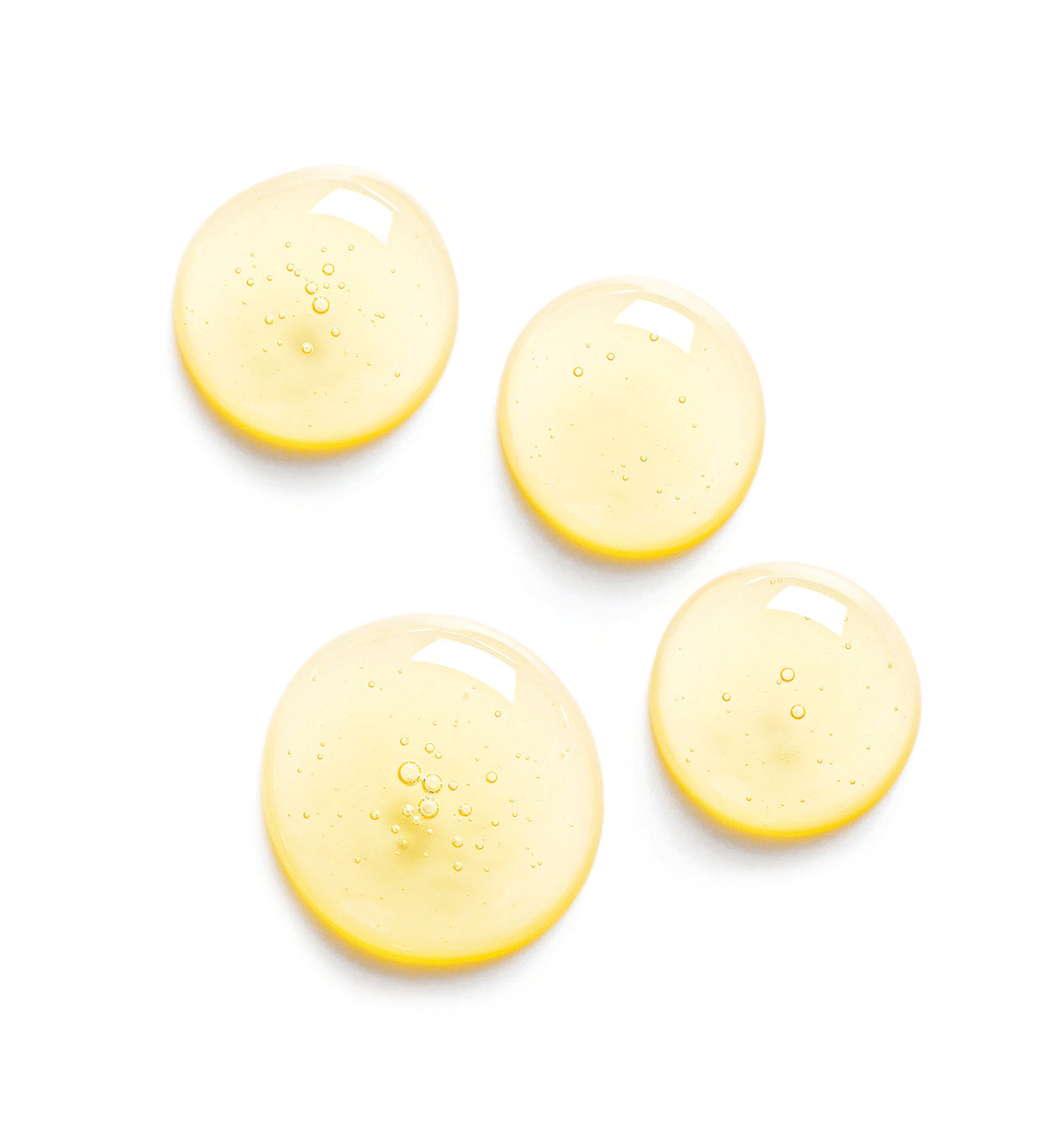 four droplets of jojoba oil on a white surface